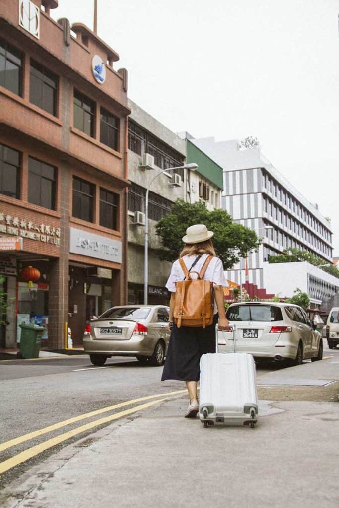 A Woman Walking Down A City Street With A Suitcase Packed For A Business Trip