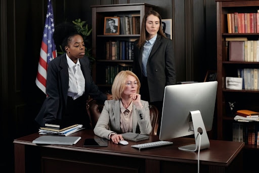 Three Women Wearing Business Professional Attire Working In An Office