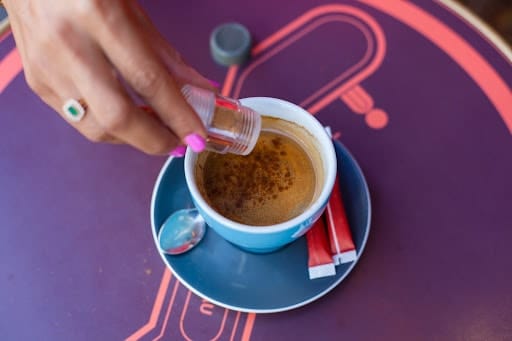 Woman Adding cinnamon to coffee to avoid sugar crashes