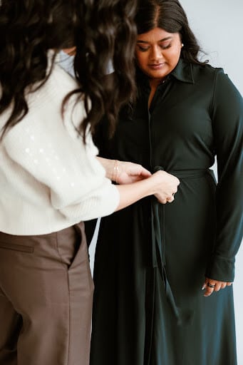 Stylist helping woman get dressed 