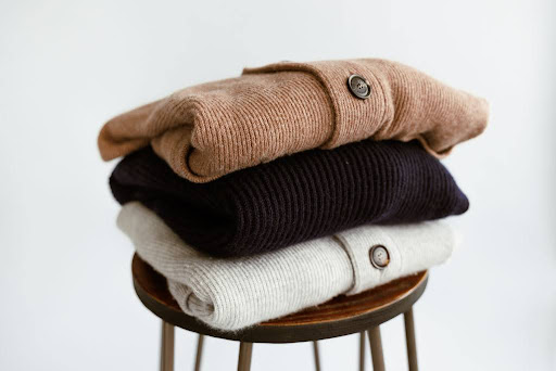 Folded sweaters on a stool